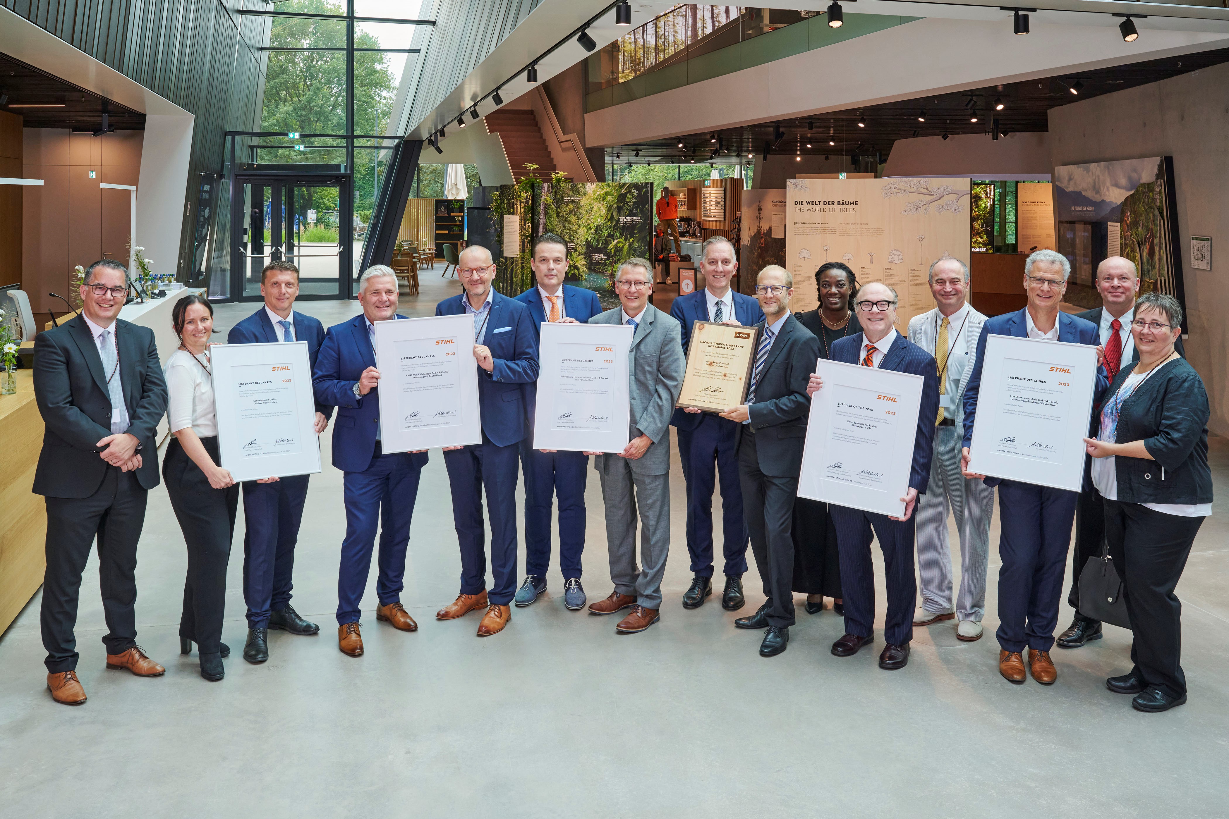 Martin Schwarz, STIHL Vorstand Produktion und Materialwirtschaft (links), und Marc Moser, Bereichsleiter Einkauf (hinten rechts), mit den ausgezeichneten Lieferanten in der STIHL Markenwelt.